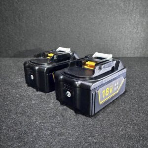 Alana presents two black Makita Battery 5Ah 18V Twin Pack power tool batteries side by side on a dark surface.