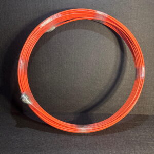 Alana’s 40 meter, 7mm orange camera cable for pan tilt setups, coiled and wrapped in clear plastic against a dark backdrop.